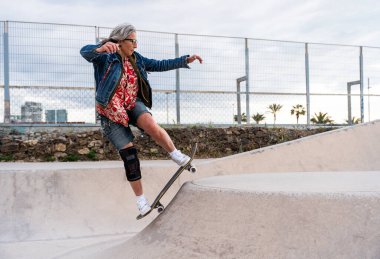 Paten parkında kaykay yapan güzel, aktif bir son sınıf öğrencisi kadın kaykaycı olgun bir kadın kaykaycı eğleniyor, yaşlılar, modern yaşam tarzı ve yeşil hareketlilik kavramları var.