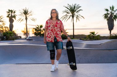 Paten parkında kaykay yapan güzel, aktif bir son sınıf öğrencisi kadın kaykaycı olgun bir kadın kaykaycı eğleniyor, yaşlılar, modern yaşam tarzı ve yeşil hareketlilik kavramları var.