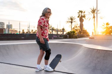 Paten parkında kaykay yapan güzel, aktif bir son sınıf öğrencisi kadın kaykaycı olgun bir kadın kaykaycı eğleniyor, yaşlılar, modern yaşam tarzı ve yeşil hareketlilik kavramları var.