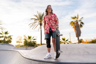 Paten parkında kaykay yapan güzel, aktif bir son sınıf öğrencisi kadın kaykaycı olgun bir kadın kaykaycı eğleniyor, yaşlılar, modern yaşam tarzı ve yeşil hareketlilik kavramları var.