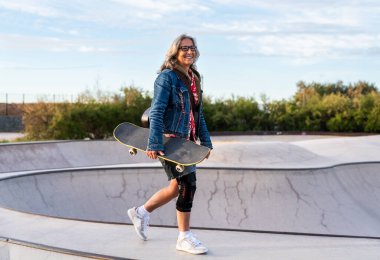 Paten parkında kaykay yapan güzel, aktif bir son sınıf öğrencisi kadın kaykaycı olgun bir kadın kaykaycı eğleniyor, yaşlılar, modern yaşam tarzı ve yeşil hareketlilik kavramları var.