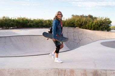 Paten parkında kaykay yapan güzel, aktif bir son sınıf öğrencisi kadın kaykaycı olgun bir kadın kaykaycı eğleniyor, yaşlılar, modern yaşam tarzı ve yeşil hareketlilik kavramları var.