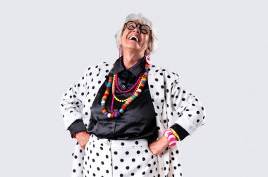 Stüdyoda gri saçlı, şık giyimli güzel bir kadın, şık bir tarzı olan neşeli, yaşlı bir büyükanne.