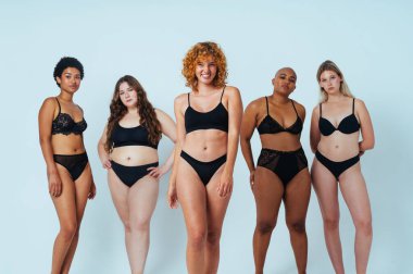 Multiethnic group of women wearing underwear with diverse kind of bodies posing in studio to celebrate diversity and self esteem  - body positive, authenticity, women's power and body acceptance concepts clipart