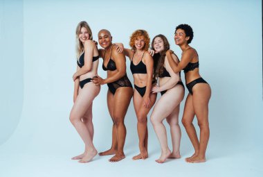 Çeşitliliği ve kendine saygıyı kutlamak için stüdyoda poz veren çok ırklı kadın iç çamaşırı giyen bir grup kadın. Vücut pozitifliği, özgünlük, kadın gücü ve beden kabulü kavramları.