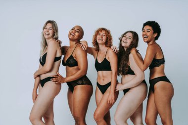 Çeşitliliği ve kendine saygıyı kutlamak için stüdyoda poz veren çok ırklı kadın iç çamaşırı giyen bir grup kadın. Vücut pozitifliği, özgünlük, kadın gücü ve beden kabulü kavramları.