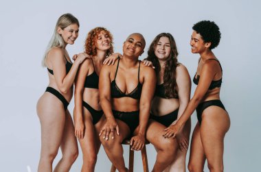 Çeşitliliği ve kendine saygıyı kutlamak için stüdyoda poz veren çok ırklı kadın iç çamaşırı giyen bir grup kadın. Vücut pozitifliği, özgünlük, kadın gücü ve beden kabulü kavramları.