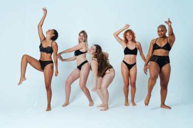 Çeşitliliği ve kendine saygıyı kutlamak için stüdyoda poz veren çok ırklı kadın iç çamaşırı giyen bir grup kadın. Vücut pozitifliği, özgünlük, kadın gücü ve beden kabulü kavramları.