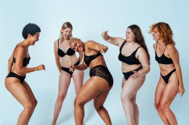 Çeşitliliği ve kendine saygıyı kutlamak için stüdyoda poz veren çok ırklı kadın iç çamaşırı giyen bir grup kadın. Vücut pozitifliği, özgünlük, kadın gücü ve beden kabulü kavramları.