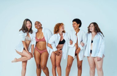 Çeşitliliği ve kendine saygıyı kutlamak için stüdyoda poz veren çok ırklı kadın iç çamaşırı giyen bir grup kadın. Vücut pozitifliği, özgünlük, kadın gücü ve beden kabulü kavramları.