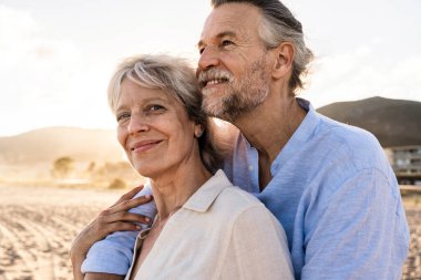 Yazın deniz kenarında flört eden mutlu bir çift, kumsalda birbirine aşık olgun evli bir çift, yaşlılar için yaşam tarzı, ilişki ve yaşam kalitesi kavramları.