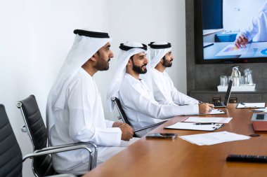 İş anlaşması için emirati kandura giyen Arap işadamları, Orta Doğu 'da uluslararası bir şirkette çalışan orta doğulu kurumsal iş adamları grubu.