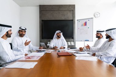 İş anlaşması için emirati kandura giyen Arap işadamları, Orta Doğu 'da uluslararası bir şirkette çalışan orta doğulu kurumsal iş adamları grubu.