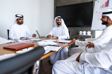 İş anlaşması için emirati kandura giyen Arap işadamları, Orta Doğu 'da uluslararası bir şirkette çalışan orta doğulu kurumsal iş adamları grubu.