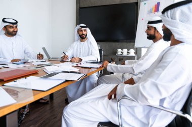 İş anlaşması için emirati kandura giyen Arap işadamları, Orta Doğu 'da uluslararası bir şirkette çalışan orta doğulu kurumsal iş adamları grubu.