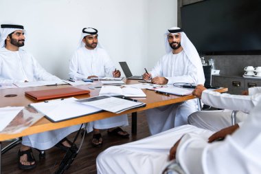 İş anlaşması için emirati kandura giyen Arap işadamları, Orta Doğu 'da uluslararası bir şirkette çalışan orta doğulu kurumsal iş adamları grubu.