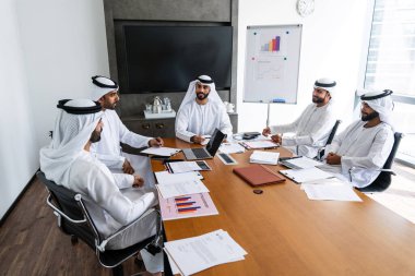 İş anlaşması için emirati kandura giyen Arap işadamları, Orta Doğu 'da uluslararası bir şirkette çalışan orta doğulu kurumsal iş adamları grubu.