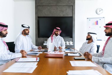 Emirati ve Suudi kandura giyen Arap işadamları iş anlaşması için Orta Doğu 'da uluslararası bir şirkette çalışan kurumsal bir iş grubu olan