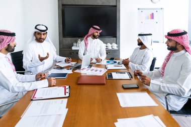 Emirati ve Suudi kandura giyen Arap işadamları iş anlaşması için Orta Doğu 'da uluslararası bir şirkette çalışan kurumsal bir iş grubu olan