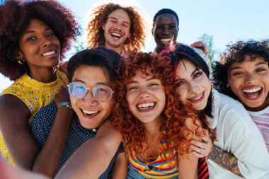 Çok ırklı bir grup genç arkadaş buluşuyor ve dışarıda eğleniyorlar- çok ırklı mutlu ve şık genç öğrenciler şehirde kaynaşıyor, gençlik kavramları, gençlerin yaşam tarzı ve çeşitliliği