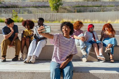 Çok ırklı bir grup genç arkadaş buluşuyor ve dışarıda eğleniyorlar- çok ırklı mutlu ve şık genç öğrenciler şehirde kaynaşıyor, gençlik kavramları, gençlerin yaşam tarzı ve çeşitliliği