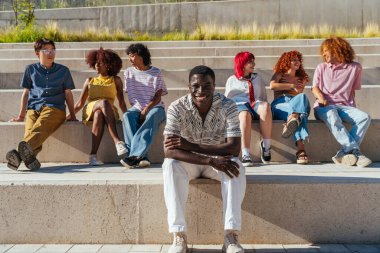 Çok ırklı bir grup genç arkadaş buluşuyor ve dışarıda eğleniyorlar- çok ırklı mutlu ve şık genç öğrenciler şehirde kaynaşıyor, gençlik kavramları, gençlerin yaşam tarzı ve çeşitliliği