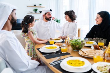 Ramazan 'dan sonra evde birlikte vakit geçiren emirati giysisi giyen mutlu Arap ailesi, Dubai' de modern bir apartman dairesinde Orta Doğulu ebeveynler ve çocuklar kaynaşıyor.