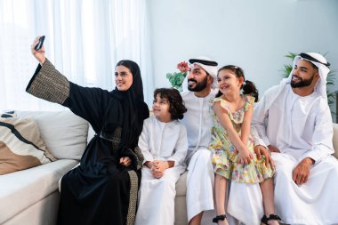 Emirati giysisi giyen mutlu Arap ailesi Dubai 'de modern bir dairede Orta Doğulu ebeveynler ve çocuklar olarak birlikte vakit geçiriyorlar.