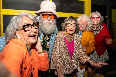 Süslü elbiseli mutlu son sınıf arkadaşları gecenin bir yarısı şehir sokaklarında parti veriyor. Şık kıyafetler giyen ve dışarıda eğlenen neşeli yaşlı insanlar.