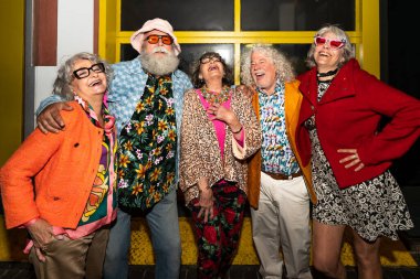 Süslü elbiseli mutlu son sınıf arkadaşları gecenin bir yarısı şehir sokaklarında parti veriyor. Şık kıyafetler giyen ve dışarıda eğlenen neşeli yaşlı insanlar.