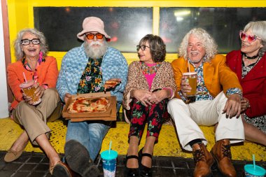 Süslü elbiseli mutlu son sınıf arkadaşları gecenin bir yarısı şehir sokaklarında parti veriyor. Şık kıyafetler giyen ve dışarıda eğlenen neşeli yaşlı insanlar.