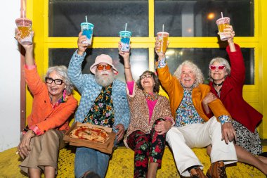 Süslü elbiseli mutlu son sınıf arkadaşları gecenin bir yarısı şehir sokaklarında parti veriyor. Şık kıyafetler giyen ve dışarıda eğlenen neşeli yaşlı insanlar.