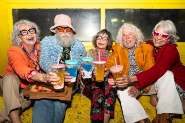 Süslü elbiseli mutlu son sınıf arkadaşları gecenin bir yarısı şehir sokaklarında parti veriyor. Şık kıyafetler giyen ve dışarıda eğlenen neşeli yaşlı insanlar.