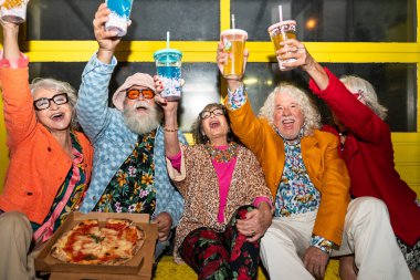 Süslü elbiseli mutlu son sınıf arkadaşları gecenin bir yarısı şehir sokaklarında parti veriyor. Şık kıyafetler giyen ve dışarıda eğlenen neşeli yaşlı insanlar.