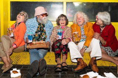 Süslü elbiseli mutlu son sınıf arkadaşları gecenin bir yarısı şehir sokaklarında parti veriyor. Şık kıyafetler giyen ve dışarıda eğlenen neşeli yaşlı insanlar.