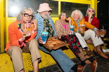 Süslü elbiseli mutlu son sınıf arkadaşları gecenin bir yarısı şehir sokaklarında parti veriyor. Şık kıyafetler giyen ve dışarıda eğlenen neşeli yaşlı insanlar.