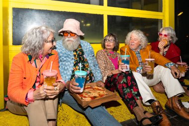 Süslü elbiseli mutlu son sınıf arkadaşları gecenin bir yarısı şehir sokaklarında parti veriyor. Şık kıyafetler giyen ve dışarıda eğlenen neşeli yaşlı insanlar.