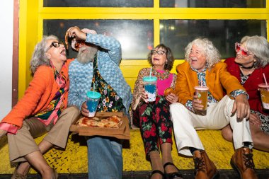 Süslü elbiseli mutlu son sınıf arkadaşları gecenin bir yarısı şehir sokaklarında parti veriyor. Şık kıyafetler giyen ve dışarıda eğlenen neşeli yaşlı insanlar.