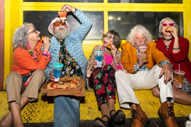 Süslü elbiseli mutlu son sınıf arkadaşları gecenin bir yarısı şehir sokaklarında parti veriyor. Şık kıyafetler giyen ve dışarıda eğlenen neşeli yaşlı insanlar.