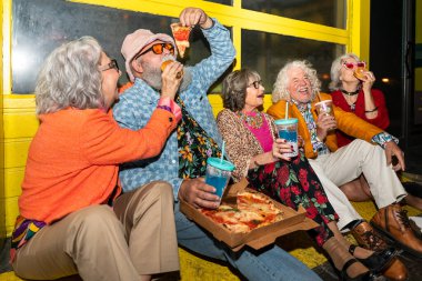 Süslü elbiseli mutlu son sınıf arkadaşları gecenin bir yarısı şehir sokaklarında parti veriyor. Şık kıyafetler giyen ve dışarıda eğlenen neşeli yaşlı insanlar.