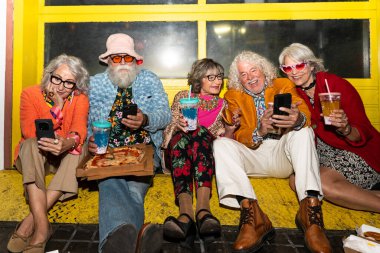 Süslü elbiseli mutlu son sınıf arkadaşları gecenin bir yarısı şehir sokaklarında parti veriyor. Şık kıyafetler giyen ve dışarıda eğlenen neşeli yaşlı insanlar.