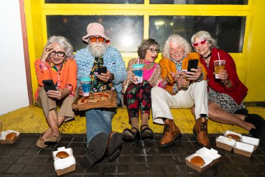 Süslü elbiseli mutlu son sınıf arkadaşları gecenin bir yarısı şehir sokaklarında parti veriyor. Şık kıyafetler giyen ve dışarıda eğlenen neşeli yaşlı insanlar.