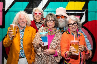 Süslü elbiseli mutlu son sınıf arkadaşları gecenin bir yarısı şehir sokaklarında parti veriyor. Şık kıyafetler giyen ve dışarıda eğlenen neşeli yaşlı insanlar.