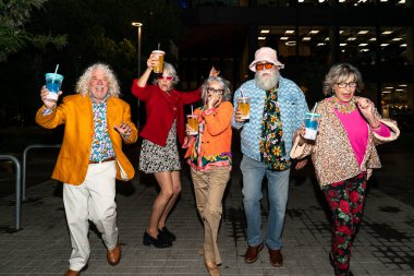 Süslü elbiseli mutlu son sınıf arkadaşları gecenin bir yarısı şehir sokaklarında parti veriyor. Şık kıyafetler giyen ve dışarıda eğlenen neşeli yaşlı insanlar.