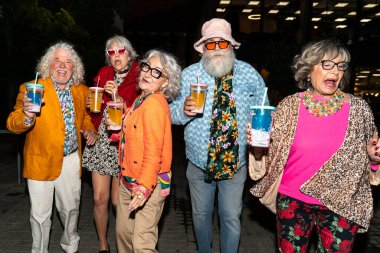 Süslü elbiseli mutlu son sınıf arkadaşları gecenin bir yarısı şehir sokaklarında parti veriyor. Şık kıyafetler giyen ve dışarıda eğlenen neşeli yaşlı insanlar.