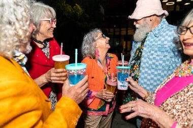 Süslü elbiseli mutlu son sınıf arkadaşları gecenin bir yarısı şehir sokaklarında parti veriyor. Şık kıyafetler giyen ve dışarıda eğlenen neşeli yaşlı insanlar.