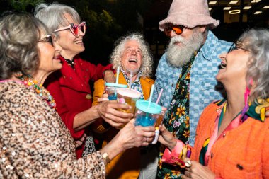 Süslü elbiseli mutlu son sınıf arkadaşları gecenin bir yarısı şehir sokaklarında parti veriyor. Şık kıyafetler giyen ve dışarıda eğlenen neşeli yaşlı insanlar.