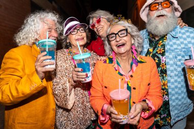 Süslü elbiseli mutlu son sınıf arkadaşları gecenin bir yarısı şehir sokaklarında parti veriyor. Şık kıyafetler giyen ve dışarıda eğlenen neşeli yaşlı insanlar.