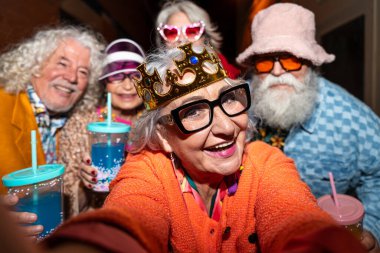 Süslü elbiseli mutlu son sınıf arkadaşları gecenin bir yarısı şehir sokaklarında parti veriyor. Şık kıyafetler giyen ve dışarıda eğlenen neşeli yaşlı insanlar.