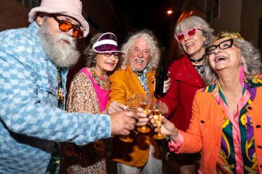 Süslü elbiseli mutlu son sınıf arkadaşları gecenin bir yarısı şehir sokaklarında parti veriyor. Şık kıyafetler giyen ve dışarıda eğlenen neşeli yaşlı insanlar.